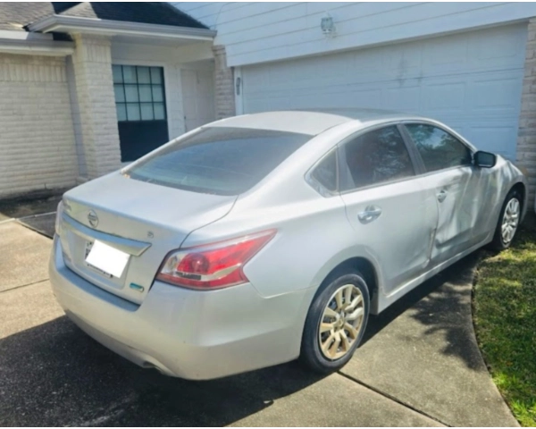 Silver Nissan Altima parked in a residential driveway in Sugar Land, TX, ready to be sold as-is with free towing from Zeus Cash For Junk Cars.