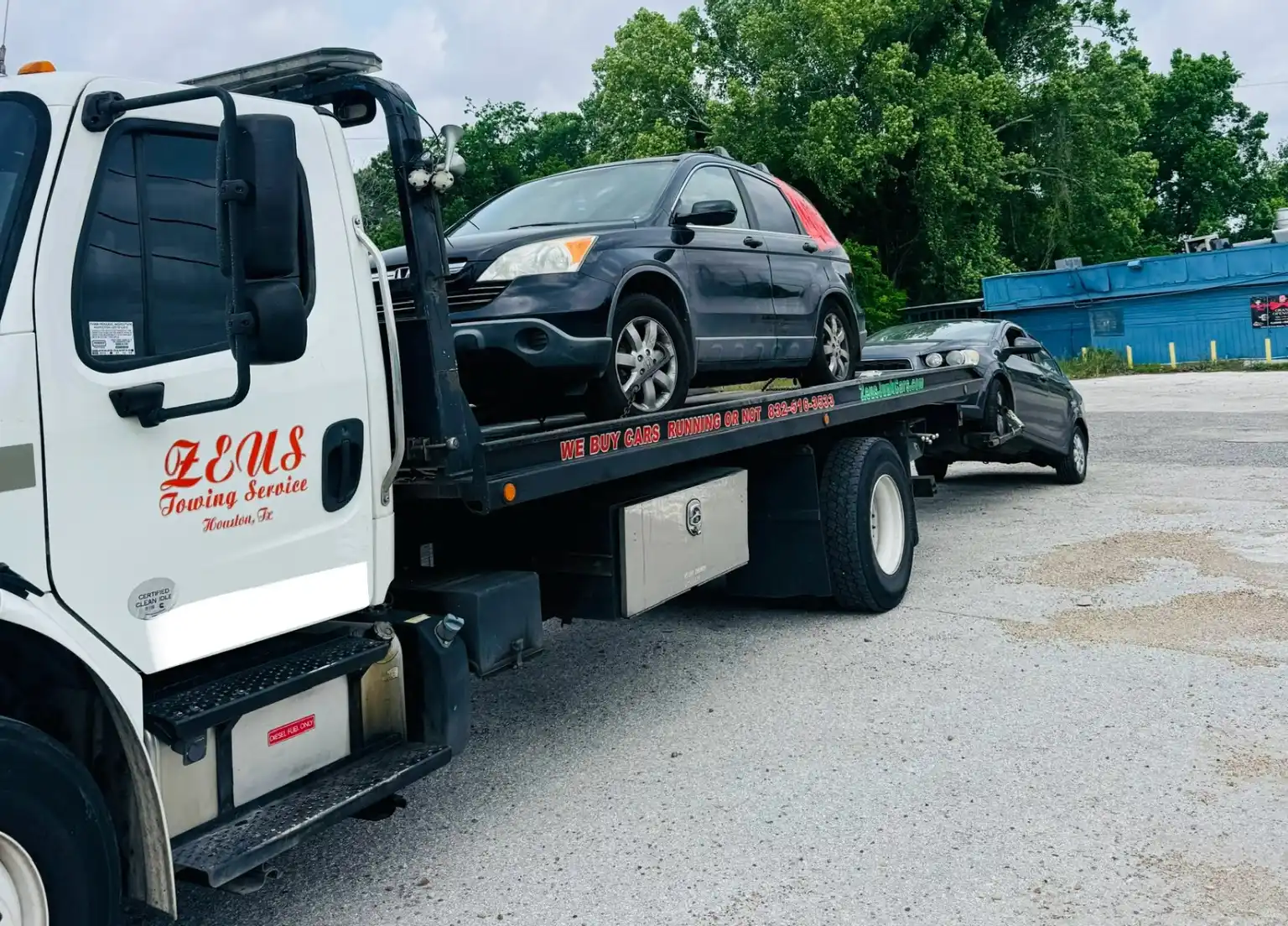 White Zeus Cash For Junk Cars flatbed tow truck hauling a black SUV and sedan for junk car pickup near Kingwood, TX