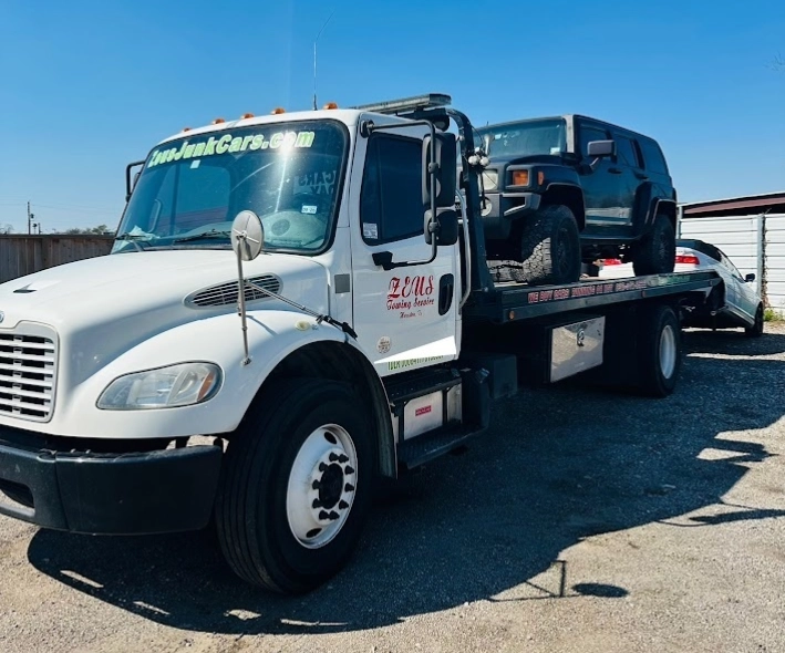 Zeus Cash For Junk Cars flatbed tow truck hauling a black Hummer in Houston,TX—free pickup and cash on pickup.