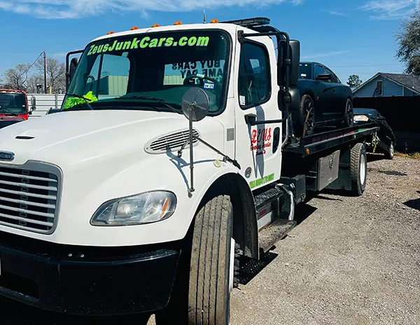 Zeus tow truck hauling a car in Bellaire, TX for cash and free towing.